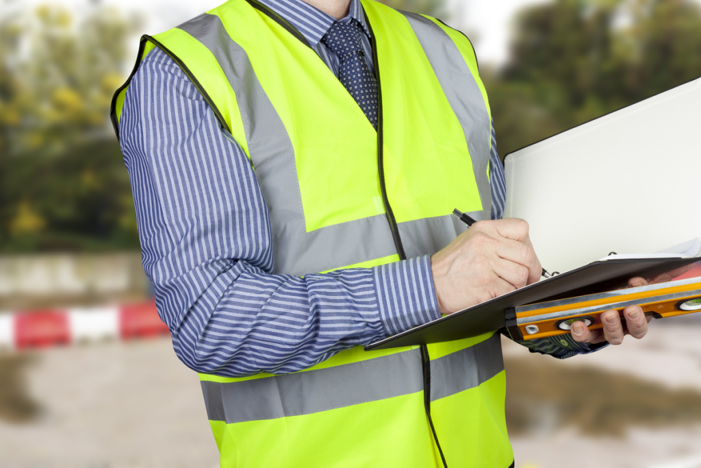 Building surveyor with spirit level writing notes in his folder