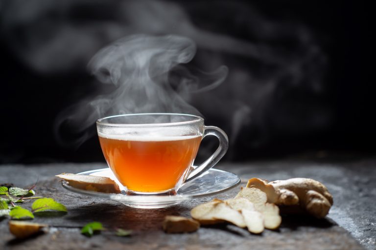 Hot Ginger tea in a glass on wood background.Hot drink