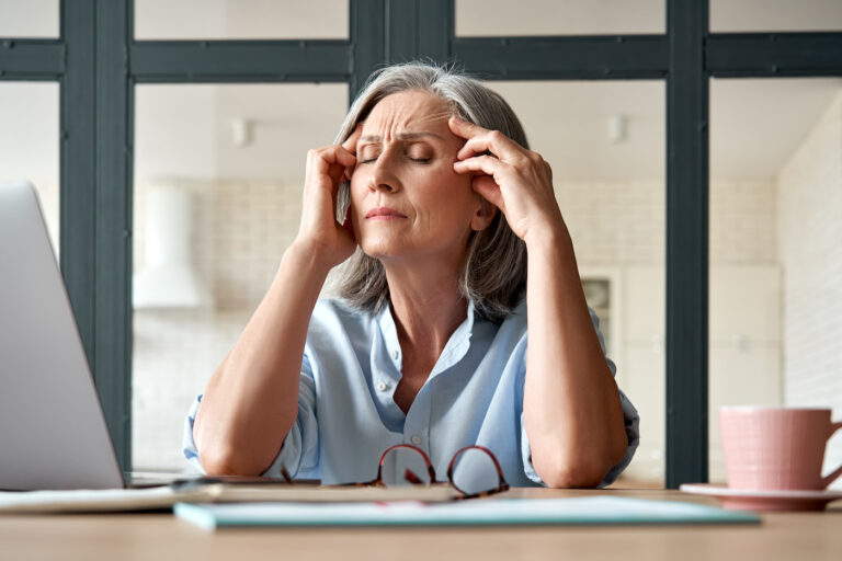 Tired stressed mature business woman suffering from menopause